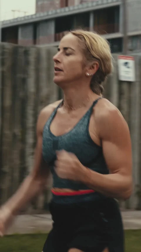 Close up of female runner's face and torso against a wooden fence Stock Footage 340046907