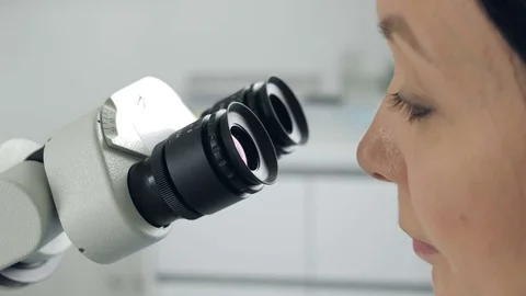 Close-up of female scientist looking through microscope. Woman dentist Stock Footage 74446151