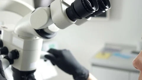 Close-up of female scientist looking through microscope. Woman dentist Stock Footage 74584620