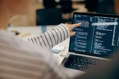 Close up of female software engineer writing code on laptop with screens setup 스톡 사진