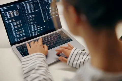 Close up of female software engineer writing code on laptop with screens setup 스톡 사진
