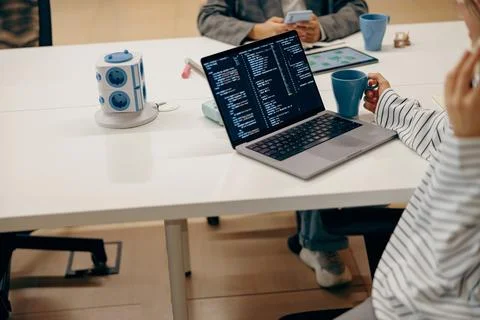 Close up of female software engineer writing code on laptop with screens setup Stock Photos