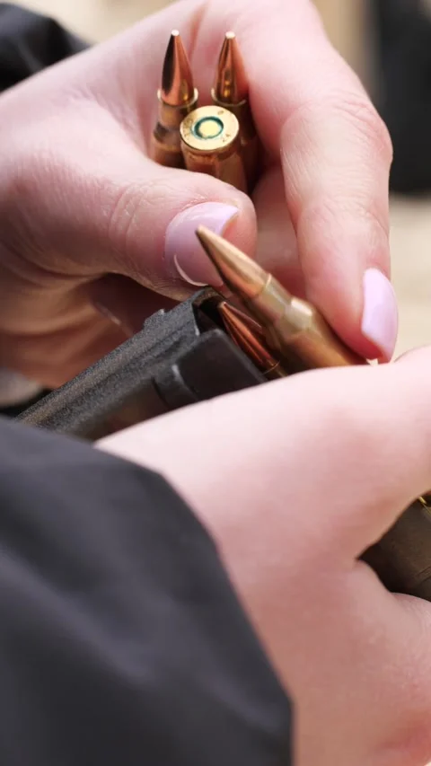 Close-up of female soldier hands loading ammunition into rifle magazine Stock Footage 333612689
