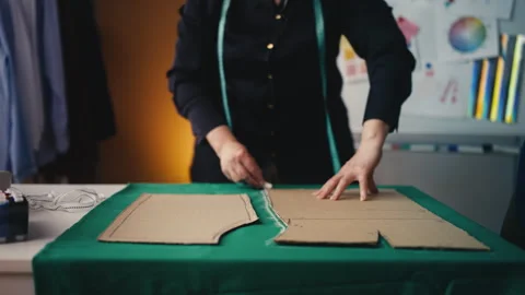 Close-up of female tailor marking fabric for sewing using paper pattern, design Stock Footage 310245114