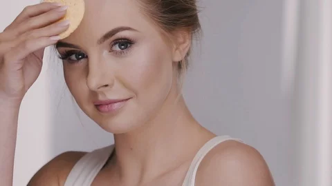 Close-up of female touching face with cotton pad isolated on grey Stock Footage 109274341
