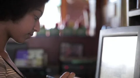 Close up female waitress with notepad at computer POS in bar 스톡 동영상 220078830