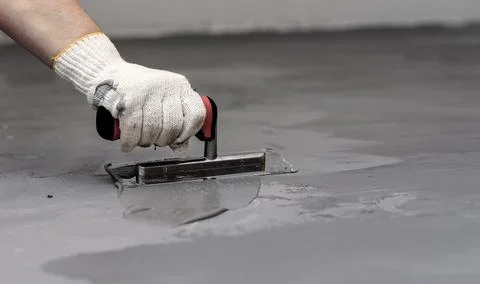 Close-up of a female worker applying microconcrete stucco to a floor with a Stock Photos