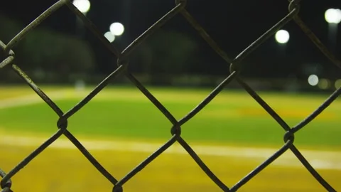 Close-up of fence with blurred baseball field in background Stock Footage 130280148