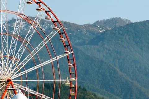 Close-up of  Ferris wheel against backdrop of mountains covered with forest. Stock Photos