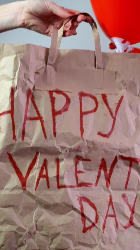 A close-up of a festive gift bag filled with red heart-shaped balloons, a perfec Stock Footage 298185762