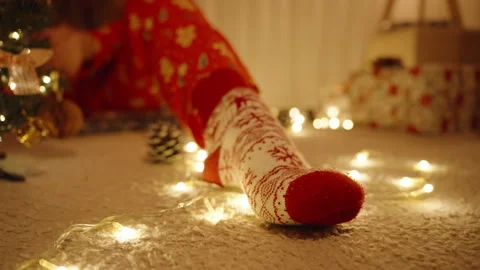 Close Up of Festive Sock with String Lights and Decorated Tree in Background on Stock Footage 316779744