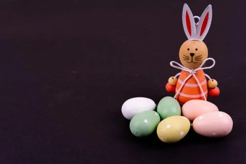 Close up of a few colorful easter eggs and a easter bunny on black background Stock Photos