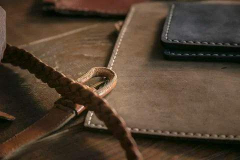 Close up of few handmade purses and braided leather strap on wooden table Stock Photos