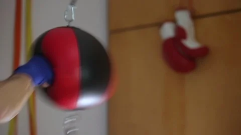 Close-up fighter's hands in boxing wraps punching double end striking bag. Vídeo Stock 104879310