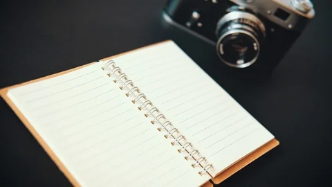 Close-up film retro camera open notebook and pen lie on the table Stock Footage 116385151