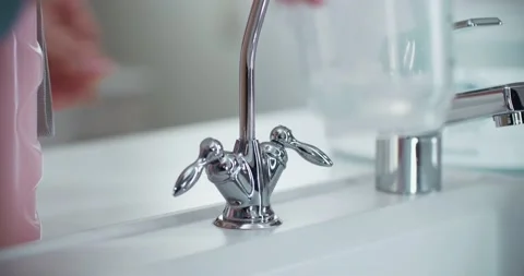 Close-up of a filter faucet in the kitchen. A woman’s hands open the faucet Vidéo 230644637