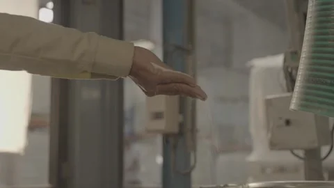 Close-up of fine white granules pouring from a hand into a machine Stock-Footage 327633073