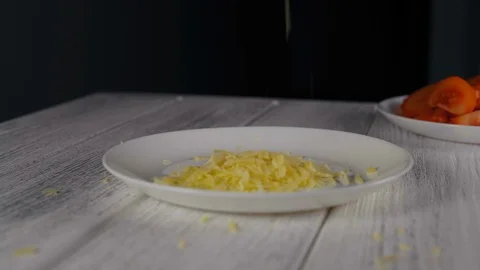 Close-up, finely grated cheese falls in a white plate Stock Footage 103640938