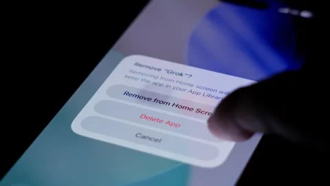 Close up of finger deleting Grok icon on smartphone screen, showing modern Stock Footage 334060018