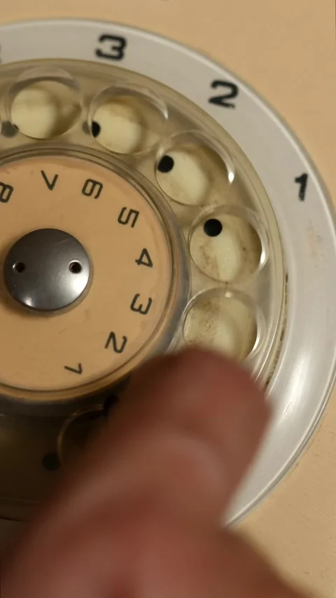 Close-up of a finger dialing a telephone number on a vintage rotary dial phone Stock Footage 339725528