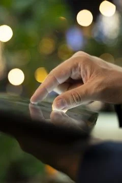 Close up of finger operating tablet touchscreen with city lights blurred Foto stock