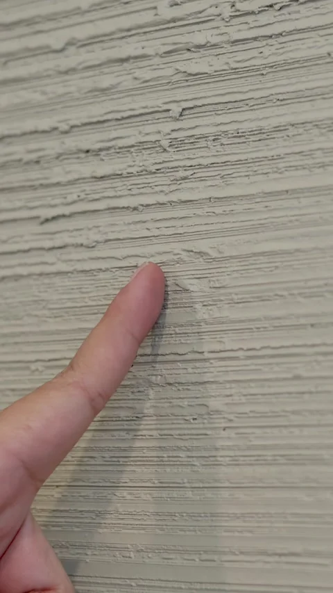 Close Up of Finger Pointing at Textured Grey Plaster Wall Stock Footage 337925708