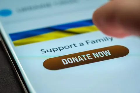Close-up finger pressing donate button on smartphone screen. Donation money 库存照片