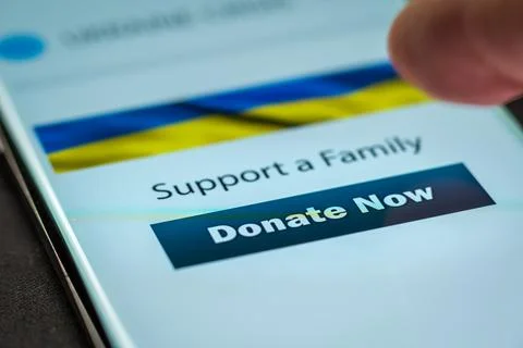Close-up finger pressing donate button on smartphone screen. Donation money 库存照片