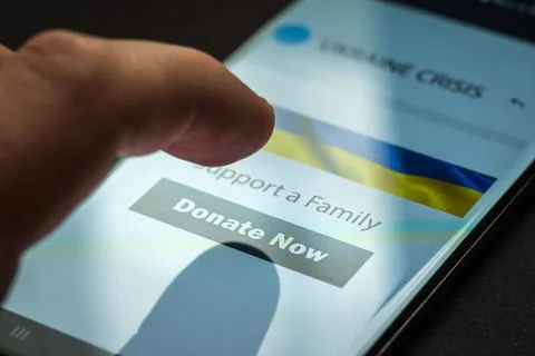 Close-up finger pressing donate button on smartphone screen. Donation money Stock-Fotos
