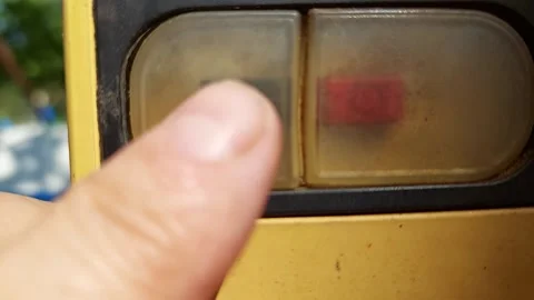 Close up of a finger pressing dust protected red and black start stop buttons on Stock Footage 336008099