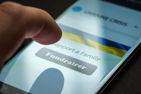 Close-up finger pressing fundraiser button on smartphone screen. Donation money Stock-Fotos
