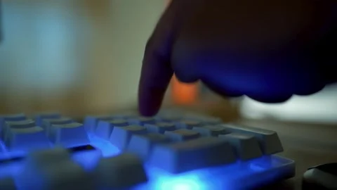 Close-up of a finger pressing a glowing keyboard key in dim lighting Stock Footage 315982136