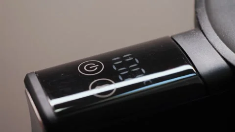 A close-up of a finger pressing a kettle on a touchpad to boil water. Convenient Stock Footage 327900843