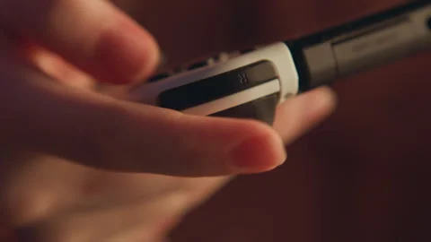Close-up finger pressing narrow control strip on handheld device, warm low-key Stock Footage 345660947