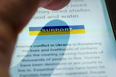 Close-up finger pressing support button over ukraine flag on smartphone screen Stock-Fotos