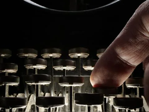 Close-up of a finger pressing a typewriter button as concept of storytelling. Stock Photos