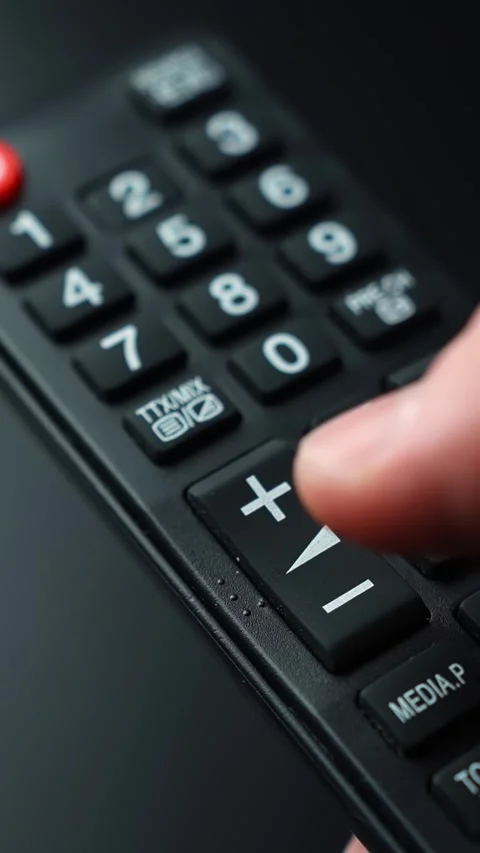 Close-up of a finger pressing volume down on a television remote control Stock Footage 331657570