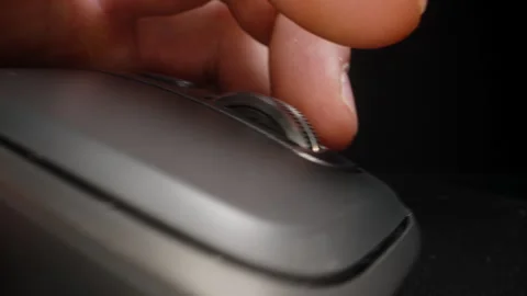 Close-up of a finger scrolling the wheel on a sleek computer mouse, showcasing Stock Footage 290986128