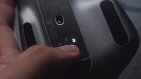 Close-up of a finger switching pairing on a wireless mouse Stock Footage 304499385
