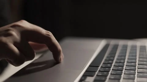 Close-up of a finger using a laptop touchpad in a dimly lit environment Stock Footage 339173899