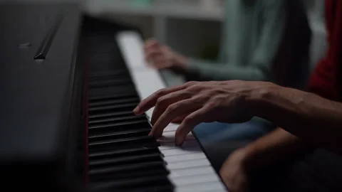 Close-up fingers of child boy playing piano, music teacher sits near and helps Stock Footage 150109040