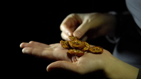 Close-up of fingers move a handful of dry apple in hand on a black background. Stock Footage 86742793