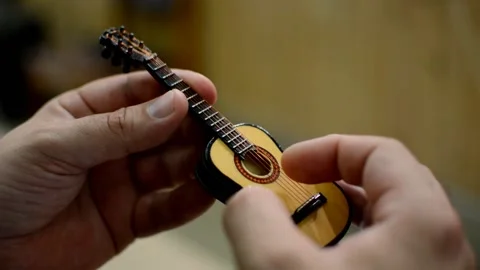 Close - up of fingers playing a small toy guitar Stock Footage 143961022