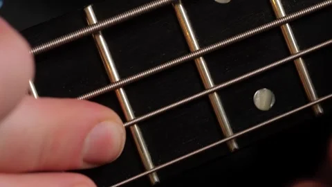 Close-up of fingers pressing strings on a bass guitar fretboard Stock Footage 301296992