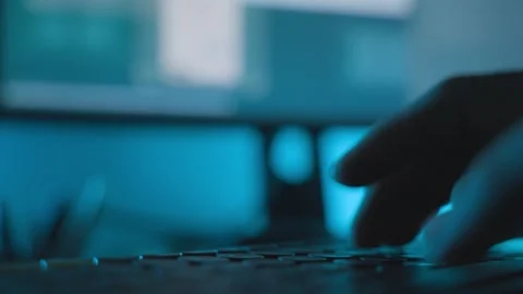 Close up fingers type on computer keyboard in dark hacker room with screen in BG Stock Footage 328026545