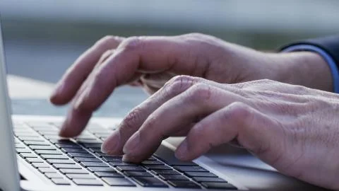 Close up of fingers typing on a laptop keyboard outdoors Stock Photos
