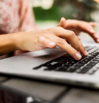 Close-Up of Fingers Typing on a Laptop Keyboard Outdoors Foto stock