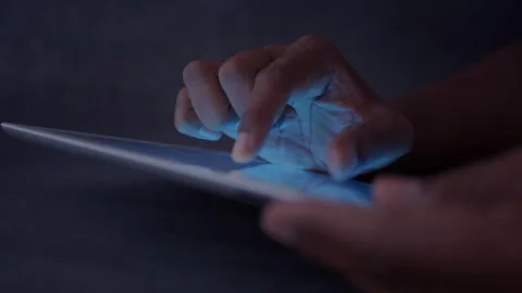 Close up of fingers using touch screen on tablet computer in dark room. Stock Footage 333258722