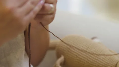 Close-up of a finished knitted doll and hands knitting in progress Stock Footage 344324762