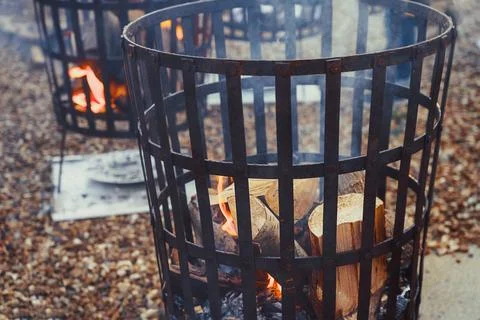 Close up fire baskets filled with burning wood and flames outdoor. Selective Stock Photos